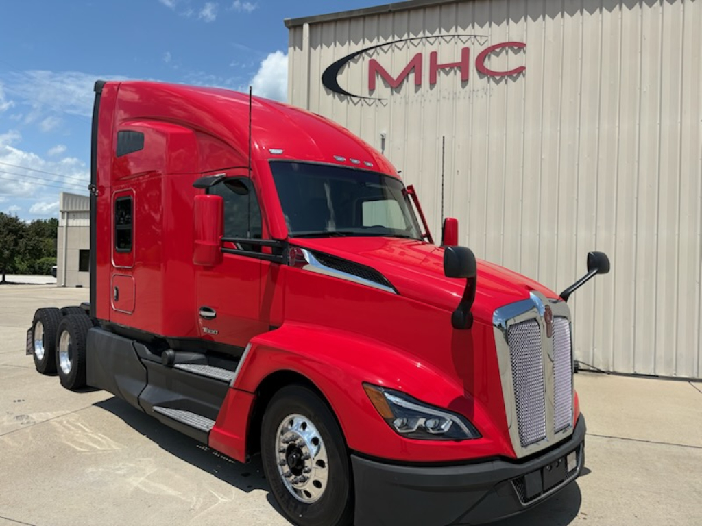 Kenworth T680 truck in red color parked in front of CMHC building showing chrome grille and sleeper cab.