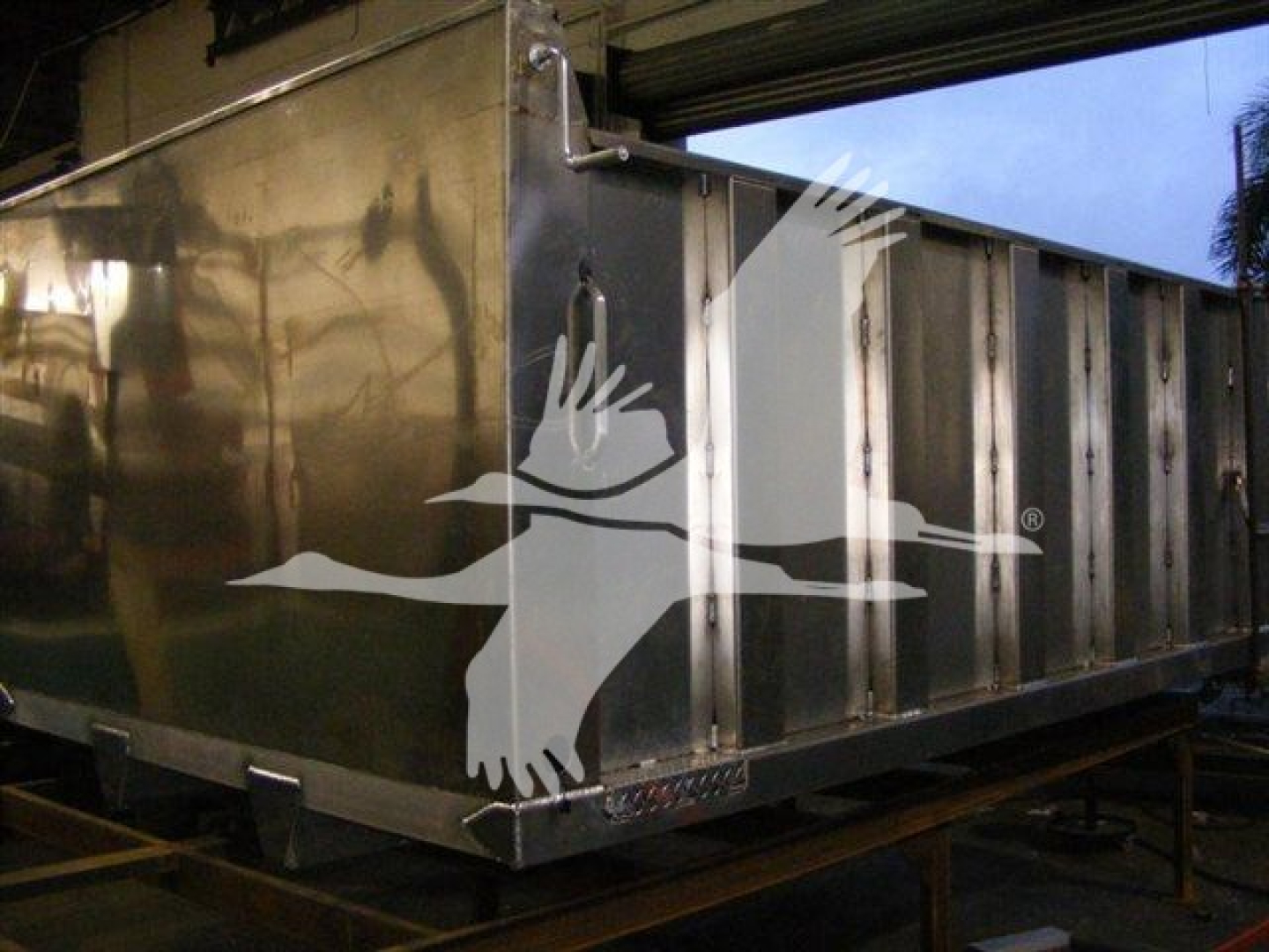 Dump trailer side showing a large white bird logo and metal panels with no visible text.