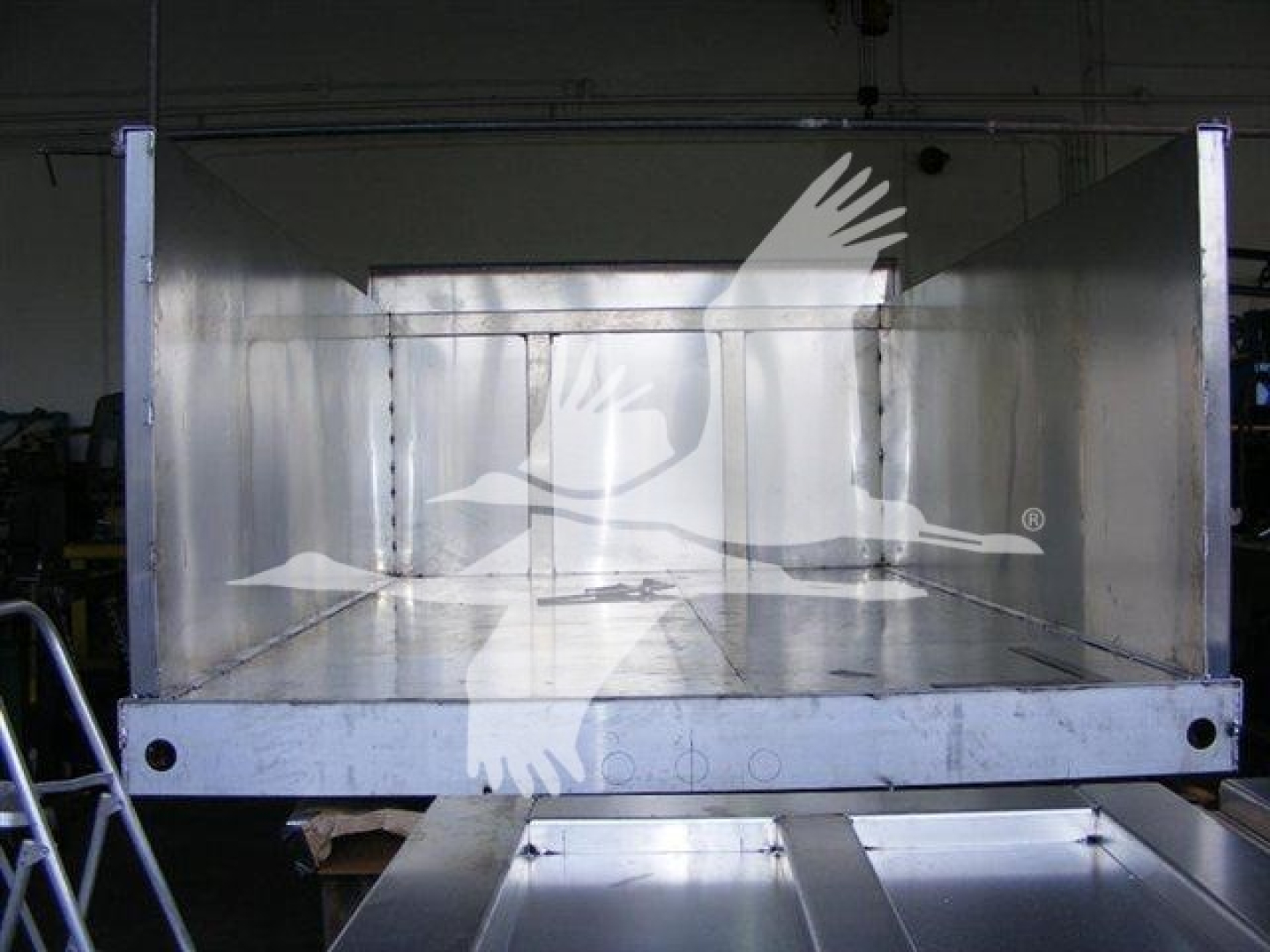 Dump truck bed showing empty aluminum dump body with open tailgate, inside reflective sides, 12 ft length, factory welds visible.