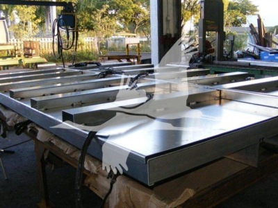 Dump truck bed frame with shiny metal surface and equipment in a shop setting showing a 12 ft Advanced Fabricators bed; stock number 12TD48PS visible in listing context.