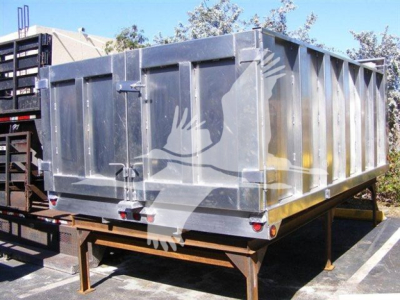 Dump truck dump bed showing metal trailer and tailgate with reflective surface