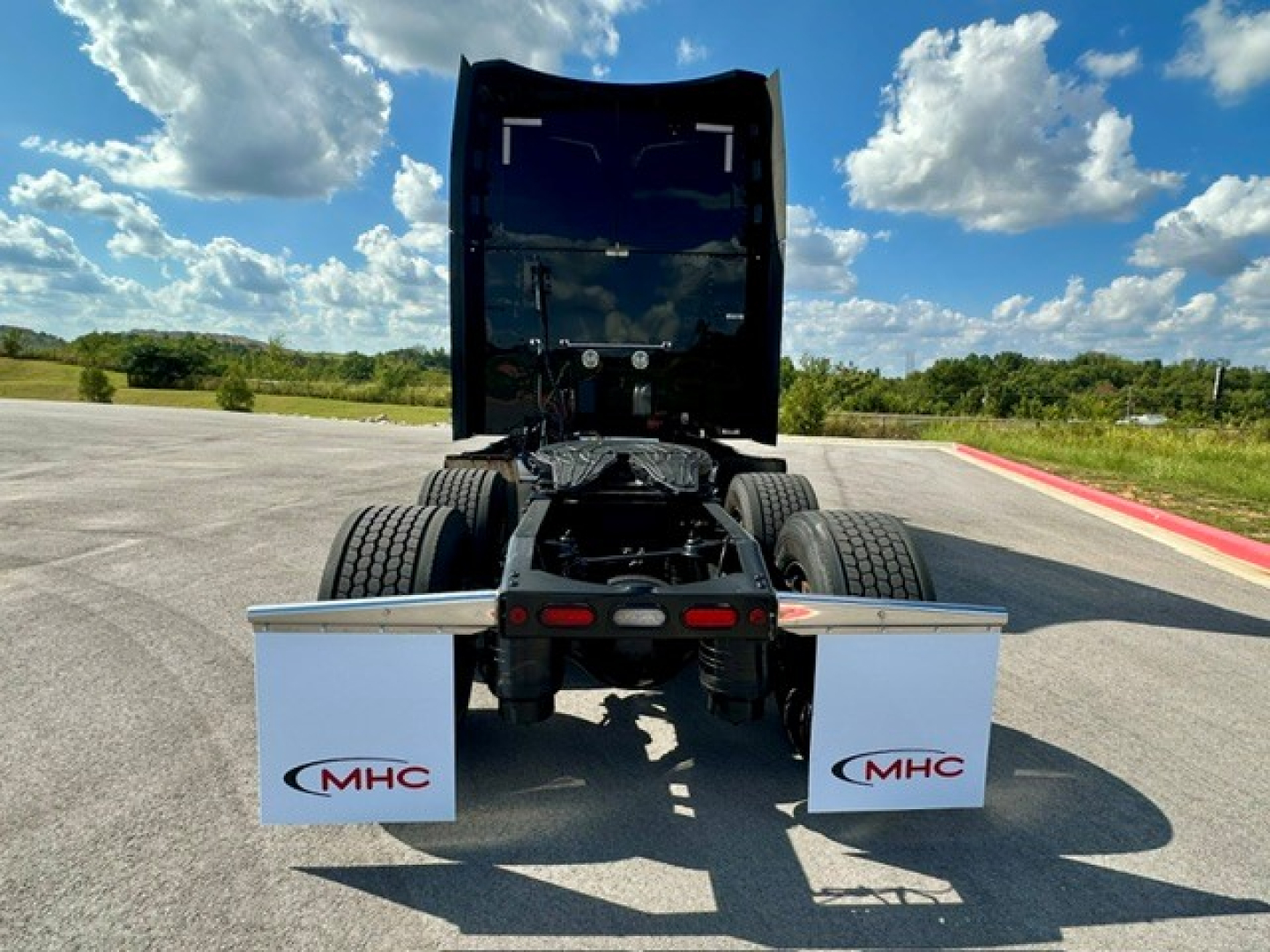 Peterbilt 579 tractor chassis back view showing mud flaps with MHC logo, chassis rails, and fifth wheel area.