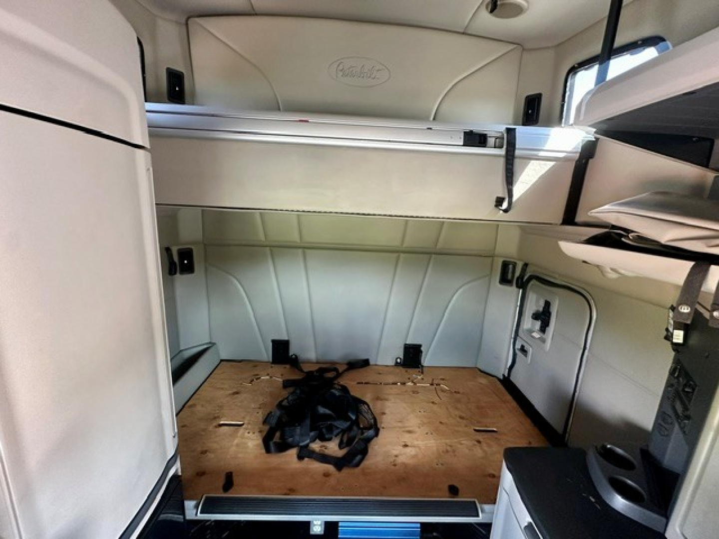 Peterbilt 579 truck interior cargo area with plywood floor and sleeper cab, side panels and storage shelves visible.