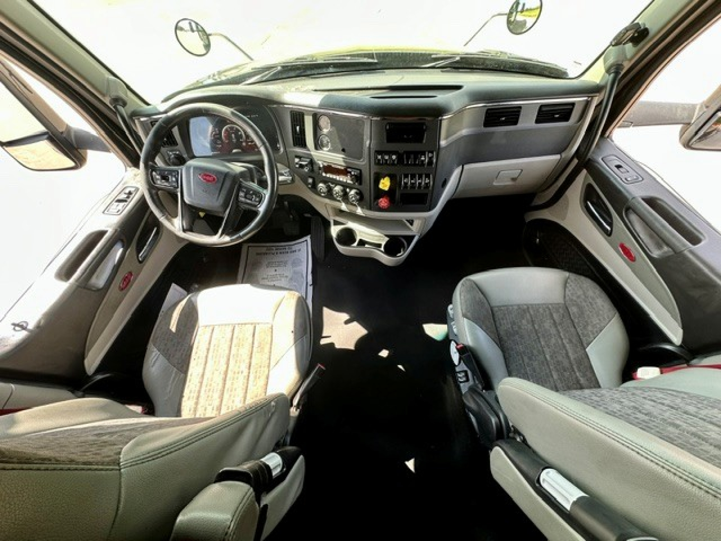 Peterbilt 579 truck interior view showing steering wheel, dashboard, and front seats.
