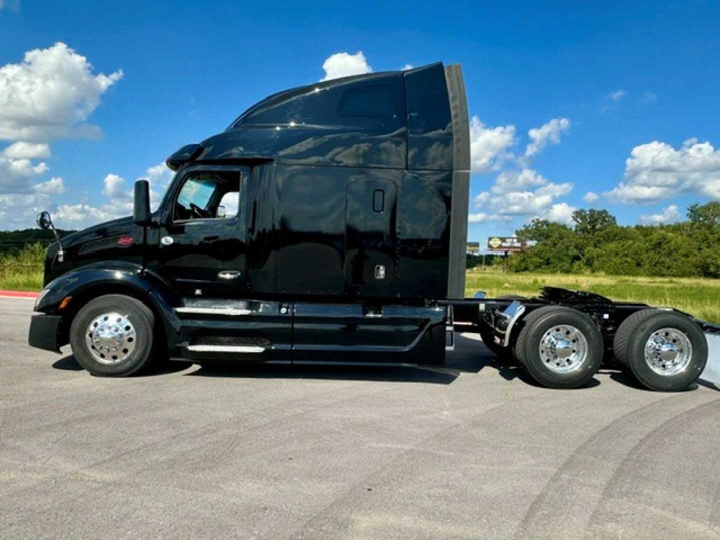Peterbilt 579 truck side view with sleeper cab, black paint, chrome wheels, dual rear axles, cab features visible.