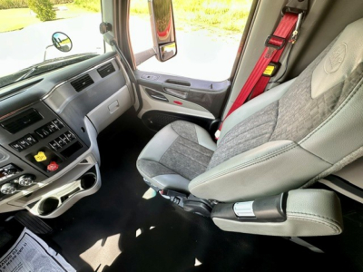 Peterbilt 579 cab interior showing driver's seat and dashboard with exposed seat belt and controls.