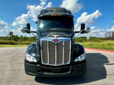 Peterbilt 579 truck front view with chrome grille and large headlights, blue exterior, daytime sky