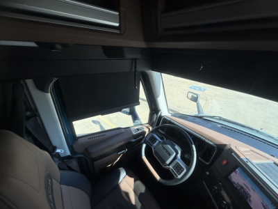 Mack PR64T76H cab interior showing steering wheel and dashboard with large side window and visor.