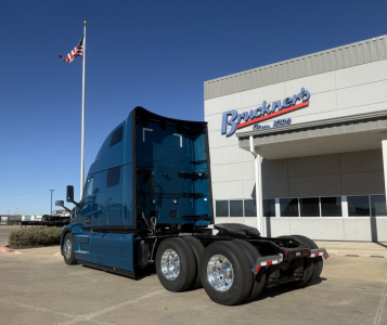 Mack PR64T76H truck tractor in blue parked outside dealership, showing rear dual axles and sleeper cab.