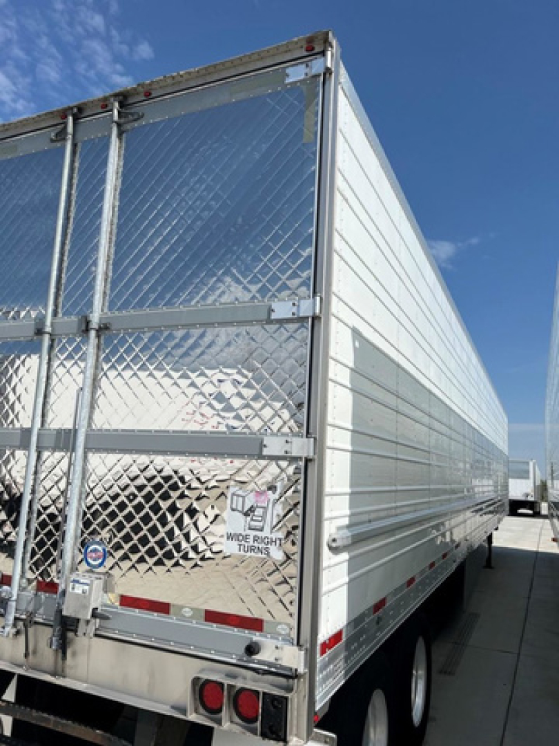 Rear and side view of a 2021 utility reefer trailer with shiny diamond plate rear gate and aluminum side panels.
