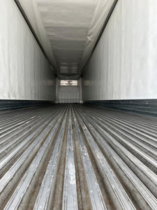 Trailer interior view of a 2021 utility reefer cargo area with ribbed floor and white walls.