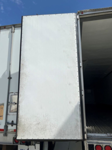 Refrigerated trailer rear door panel showing interior cargo area and side latch.