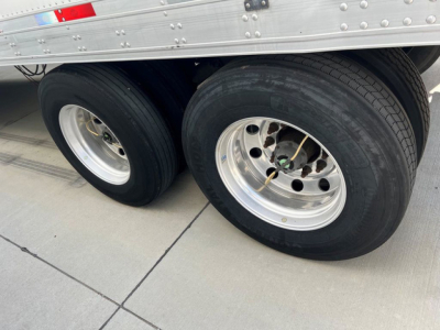 Back dual rear axle wheels of a refrigerated trailer showing tandem tires and aluminum wheels.