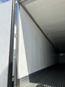 Trailer interior showing empty walls and ribbed floor of a refrigerated trailer with open door
