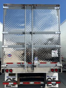 Refrigerated trailer rear showing diamond plate doors with latches, bumper lights, and license plates; various stickers and reflectors visible.