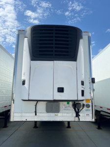 Trailer rear view of a 2021 Utility reefer with a black refrigeration unit grille and white body panels.