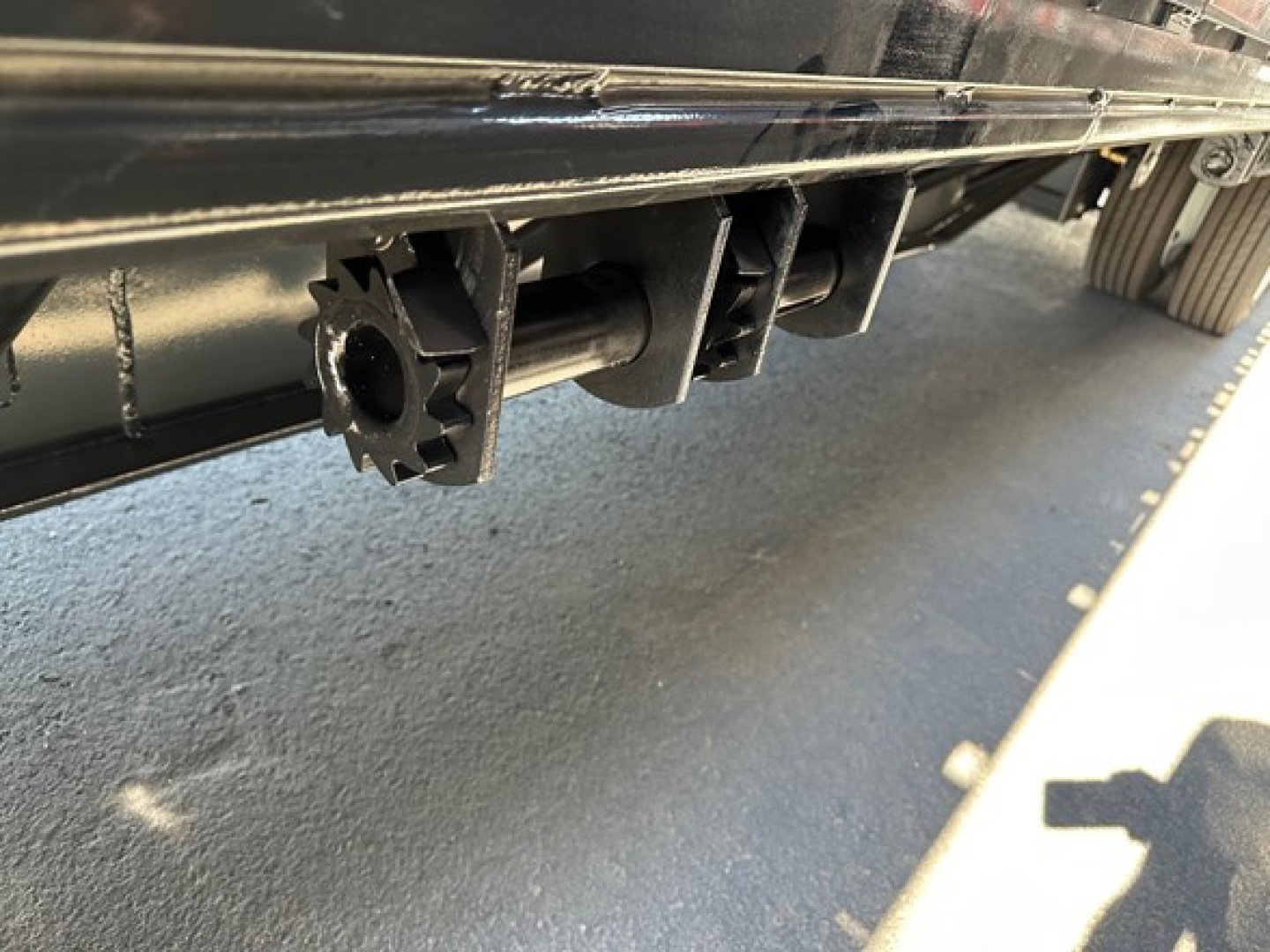 Trailer undercarriage showing coupling/drawer-like mounting bracket and a star-shaped cutter profile on a Dura Haul drop deck trailer.