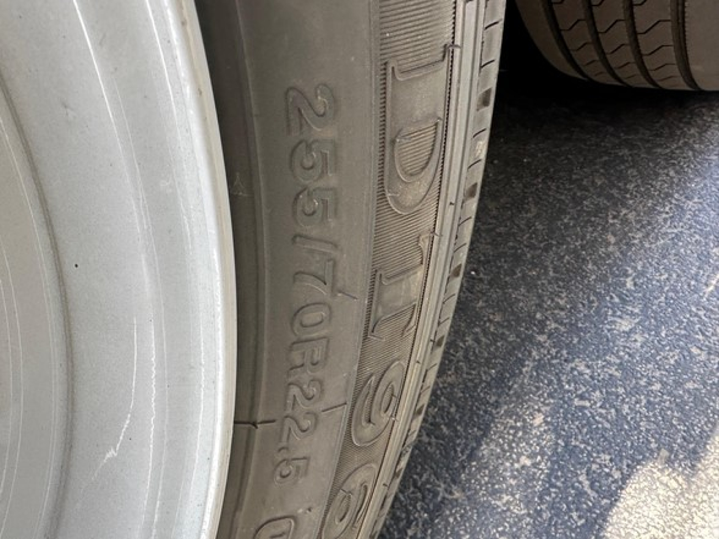 Close-up of a trailer tire showing the sidewall with the text '255/70R22.5' and part of the wheel rim.