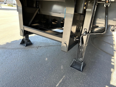 Trailer undercarriage of a closed tandem steel drop deck showing support legs and structural frame.