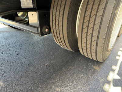 Trailer dual rear wheels with tire treads visible and undercarriage components; side label plate on chassis visible.