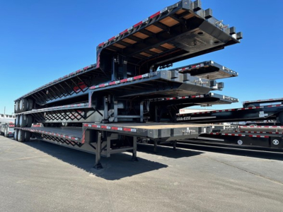 Drop deck trailers stacked on trailer yard showing multiple 2026 Dura Haul drop decks with black frames and red/white safety tape.