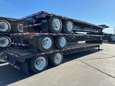 Drop deck trailer stacked on trailer base showing dual rear axles and multiple wheels, no legible text visible on components.