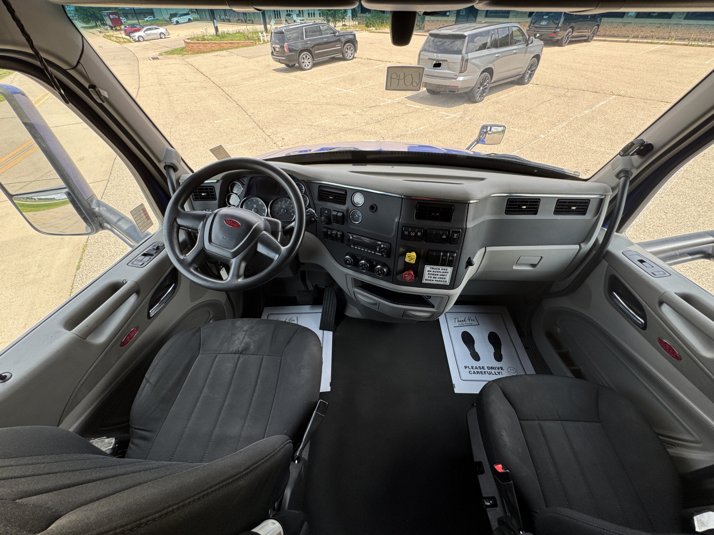 Vehicle cab interior of a 2022 Peterbilt 579 showing steering wheel, dashboard controls, and front seats.