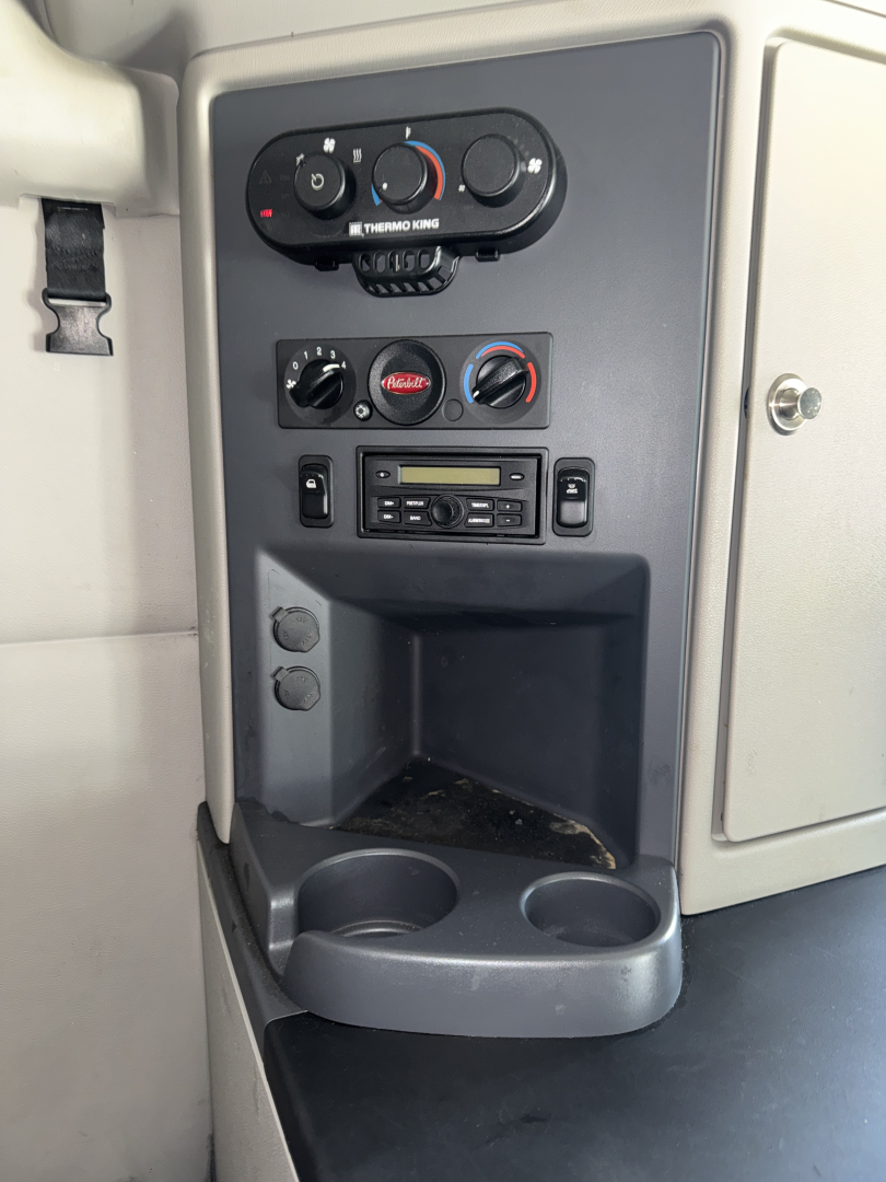 Peterbilt 579 truck interior dash area showing climate controls, radio, and cup holders in center console.