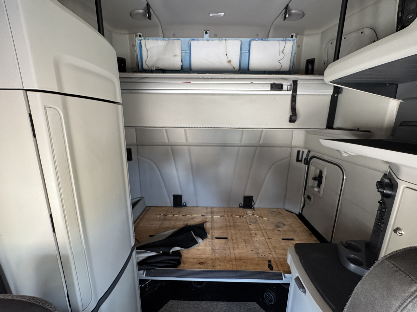 Truck interior cargo bed area of a 2022 Peterbilt 579 sleeper cab in-view, showing bare wooden floor platform and storage compartments along walls.