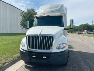 Truck cab front view showing International LT625 with large vertical grille, white paint, black bumper, and aerodynamic mirrors.