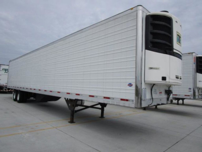 Refrigerated trailer showing front refrigeration unit and long white trailer with wheels and stand.