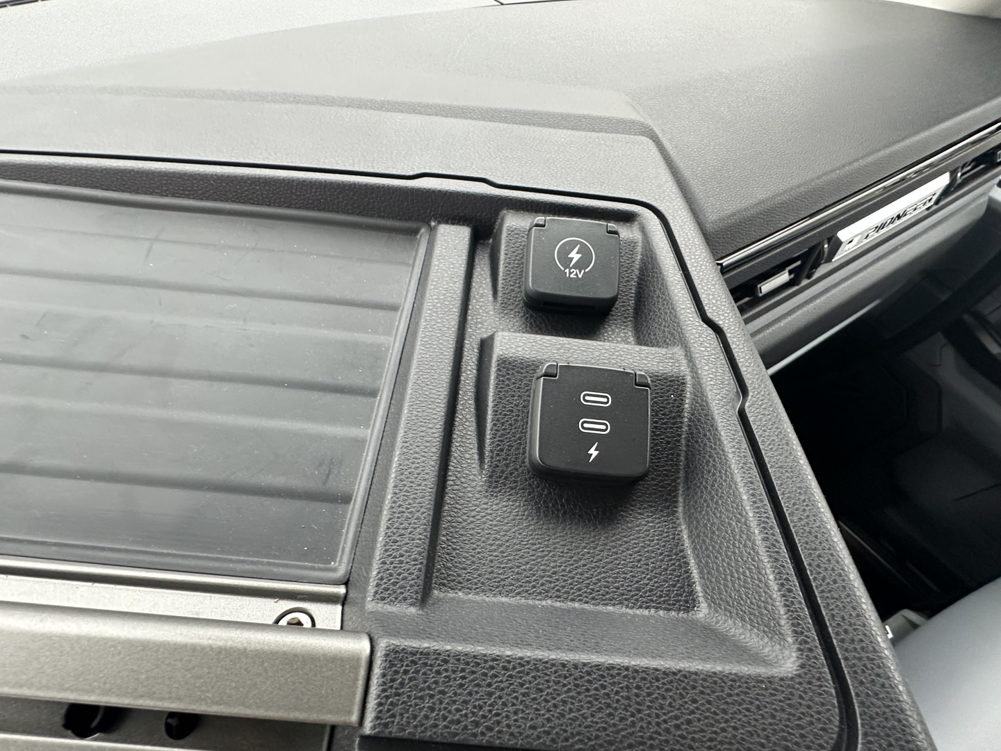 Truck cockpit area showing 12V power outlet and two USB-C: electrical ports near dashboard panel of Mack PR64T.