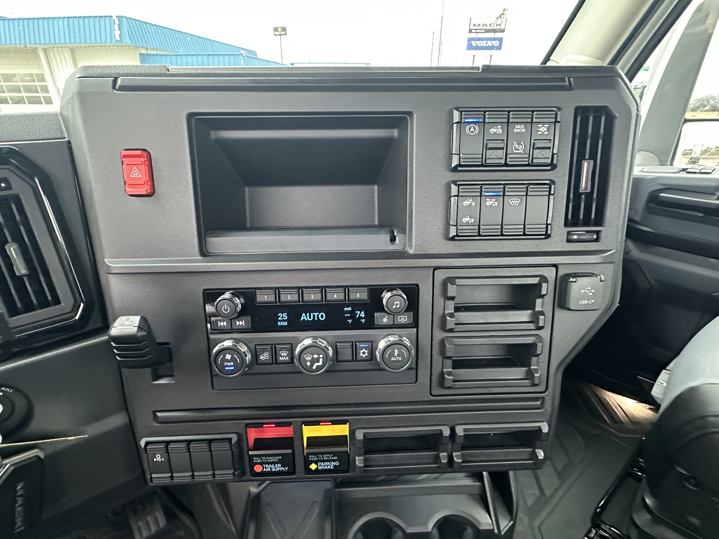 Mack PR64T dash showing ignition switches, climate controls, and storage compartments with control panels and labeled switches.