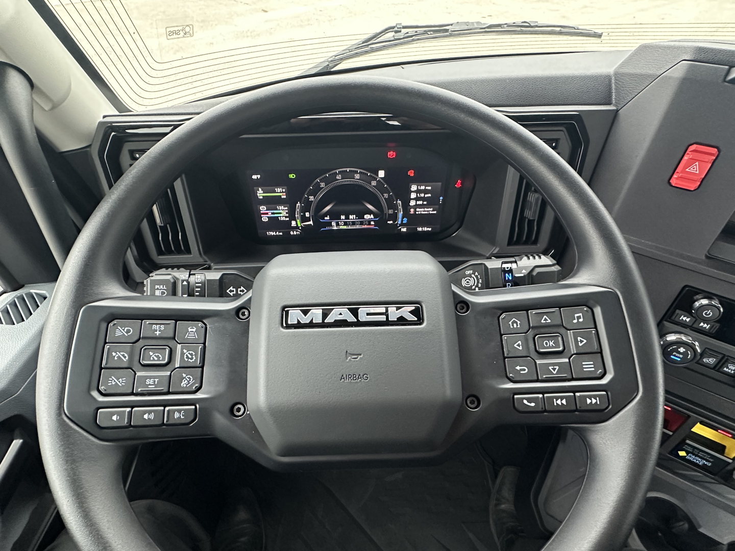 Mack PR64T interior view of steering wheel with dashboard and instrument cluster visible.