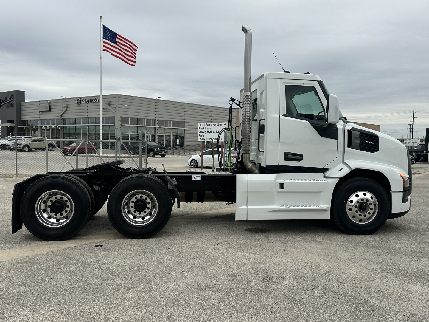 Truck chassis side view showing Mack PR64T cab with white exterior, dual rear axles, and exposed frame rails; no body attached in rear.