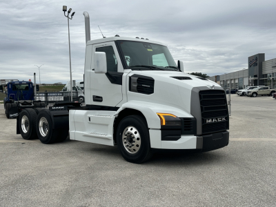 Mack PR64T conventional daycab truck side view showing white cab, black grille, dual rear axles, and chrome fuel tanks.