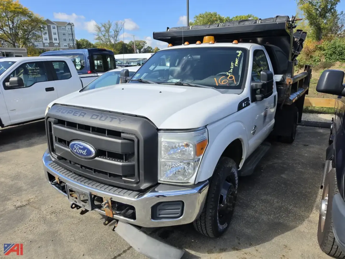 Ford F-350 Super Duty dump body truck in white, front view, dual rear wheel, grille with Ford logo, black bumper, light bar on cab, dumping bed visible.