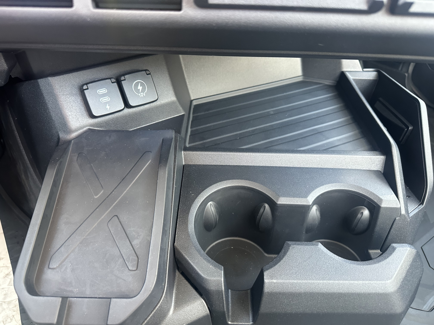Dashboard and center console of a new 2026 Mack PR64T showing cup holders and auxiliary switches.