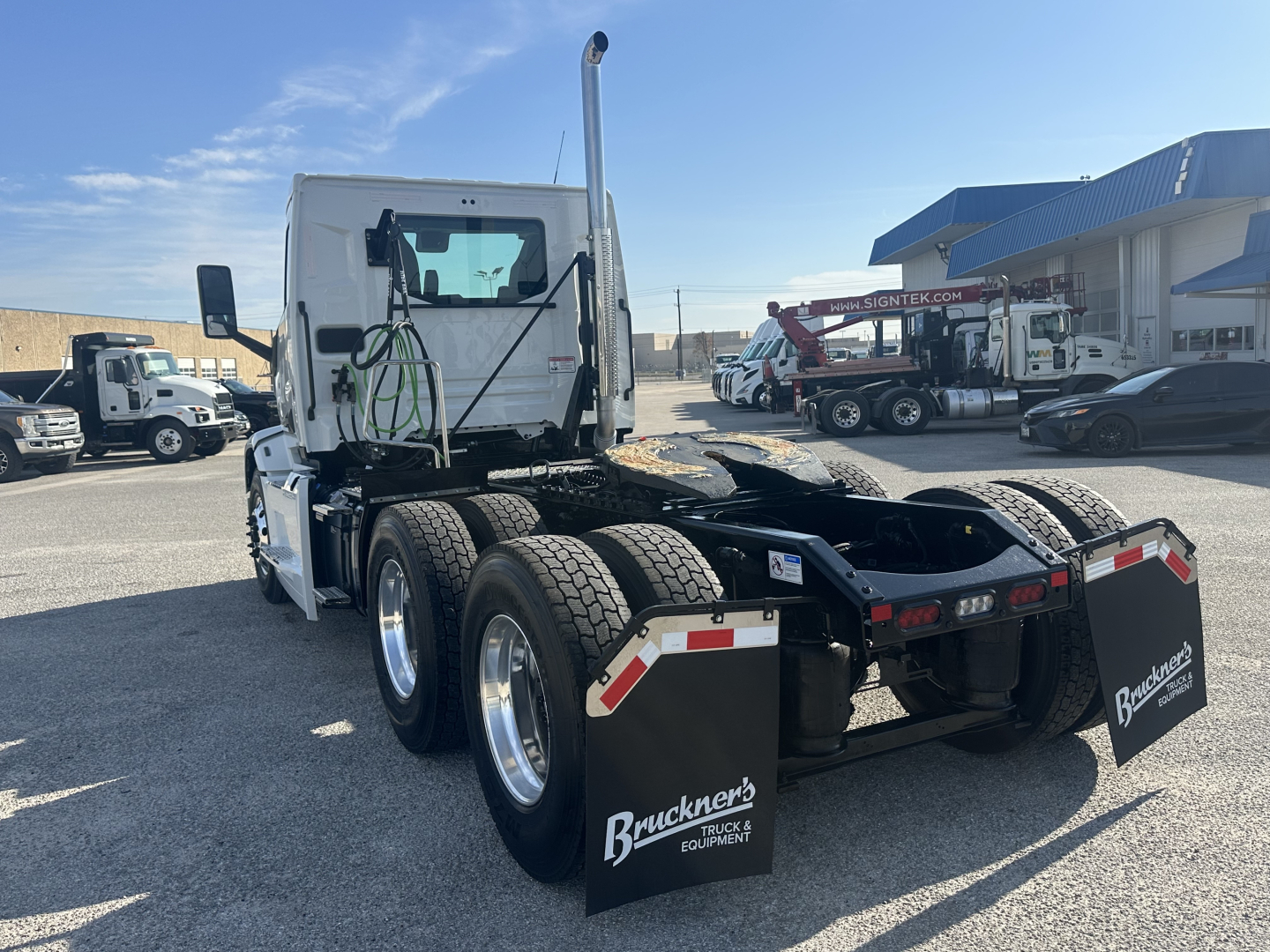 Rear view of a white 2026 Mack PR64T tractor with dual rear axles and large black mud flaps. Visible are 'Buckner's' branding on mud flaps and reflective chevrons on the rear.