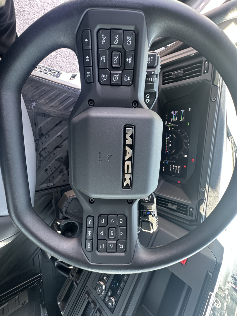 Mack PR64T steering wheel and dashboard view showing center badge and control buttons on wheel.
