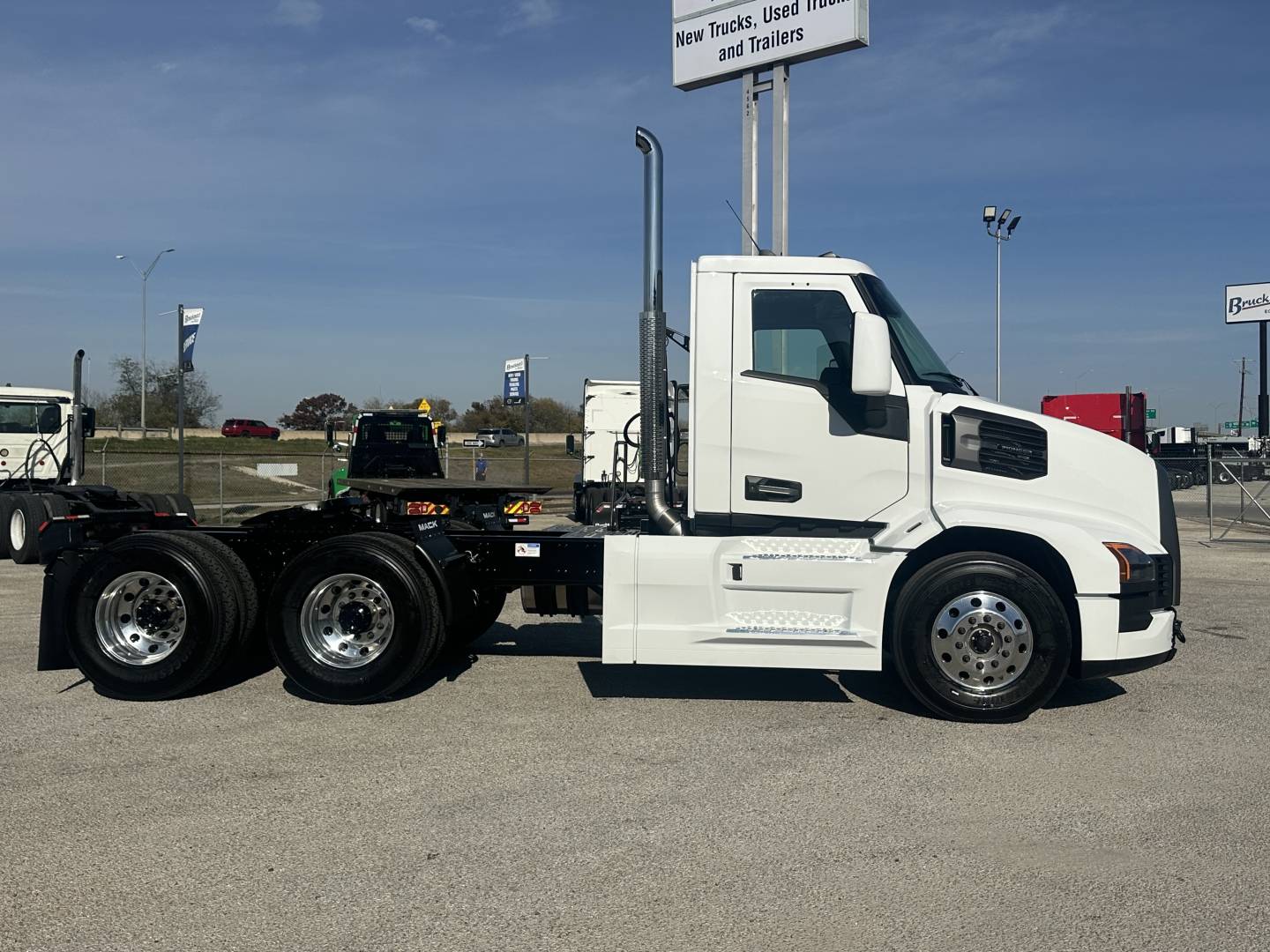 Truck chassis showing 6x4 Mack PR64T cab and white exterior with dual rear axles and chrome wheels.