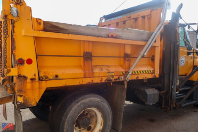 Dump truck bed and chassis of a 2011 International WorkStar 7400 with orange body, plow attachment, and rear wheel visible.