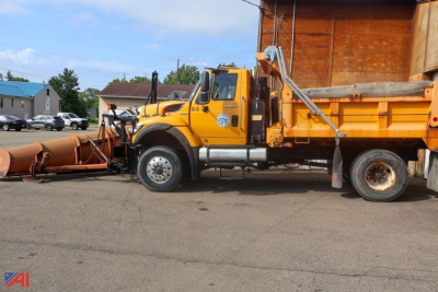International WorkStar 7400 dump truck with plow attached, yellow cab and orange dumping bed, side view.