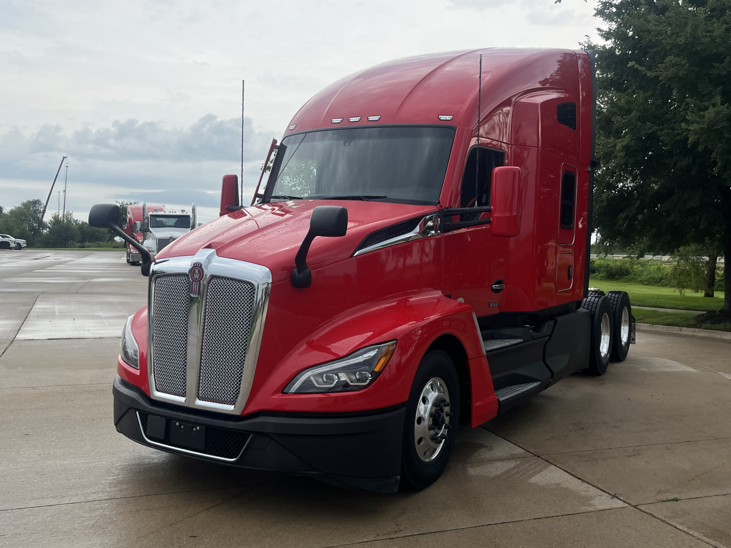 Kenworth T680 tractor unit in red, front-left view showing grille, headlights, and aerodynamic mirrors.