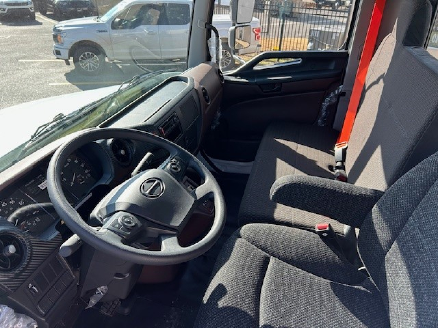 Cab and chassis interior of 2025 Hino L7 showing steering wheel with Hino emblem, dashboard, driver seat, and passenger seat.
