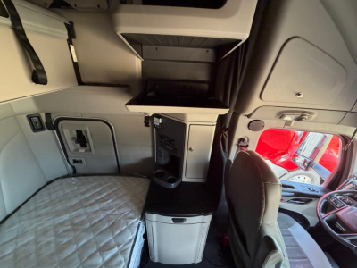 Interior of 2022 Peterbilt 579 sleeper cab showing storage cabinet, countertop, and grey upholstery.