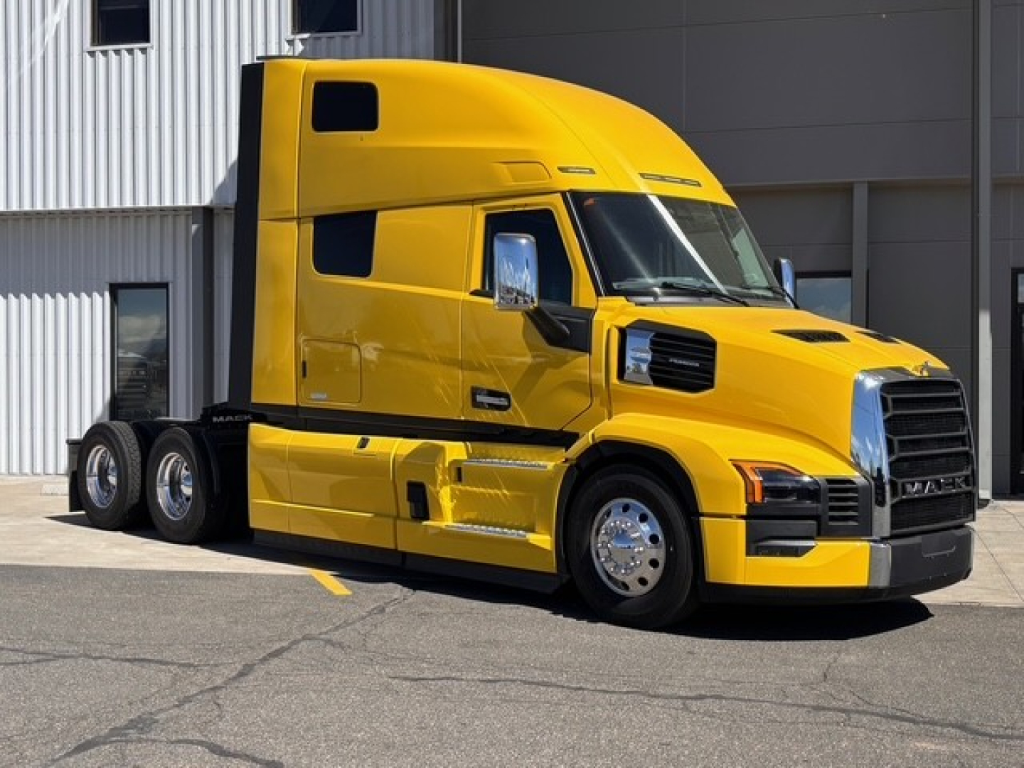 Yellow 2026 Mack PR64T76H conventional sleeper truck side view showing cab, doors, chrome mirrors, wheelbase, and black grille.