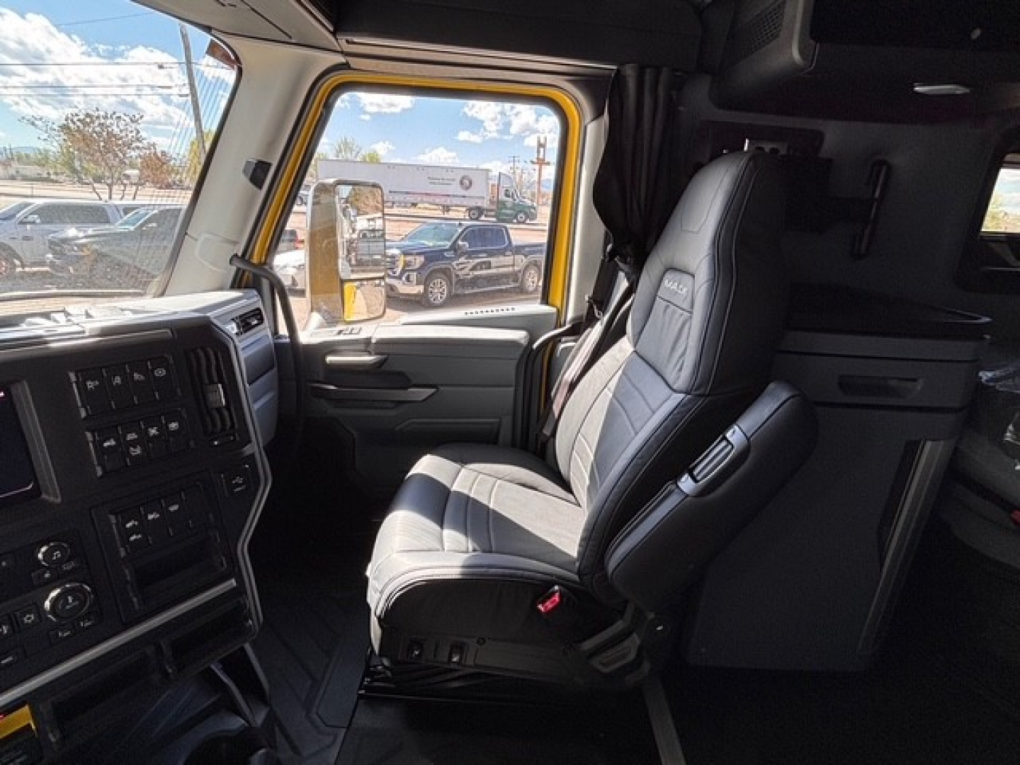 Truck cab interior of a 2026 Mack PR64T76H showing driver seat, dashboard, and window with reflection.