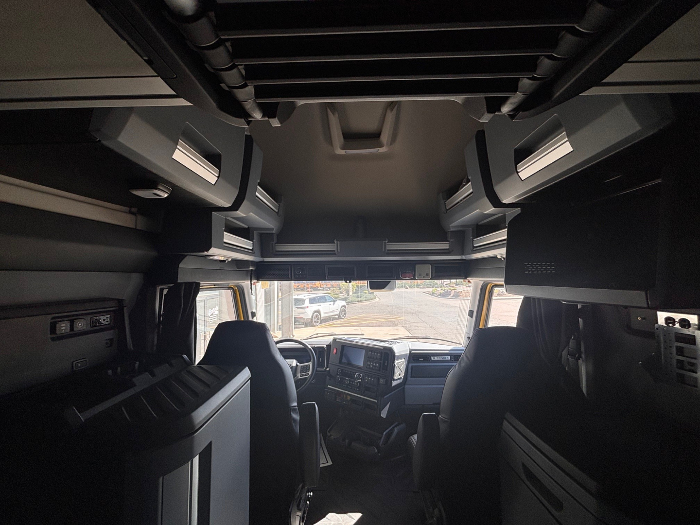 Cab interior of a new 2026 Mack PR64T76H truck showing cockpit with dashboard, overhead storage, and seats.