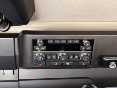Trucks dashboard control panel showing various climate and media buttons, two round knobs on either side, and a central OK button.